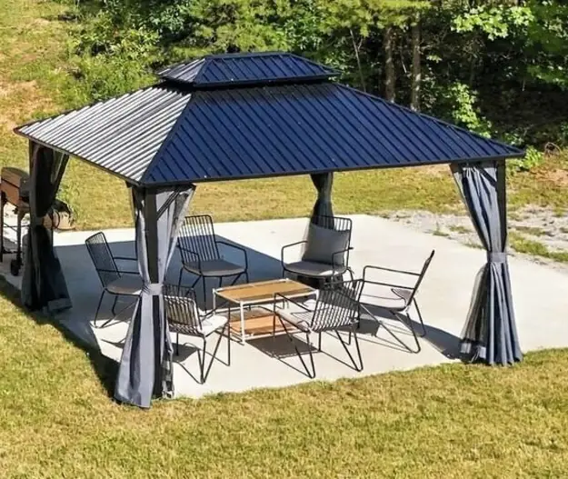 Covered gazebo with lounge chairs and a small table on a patio beside the cabin