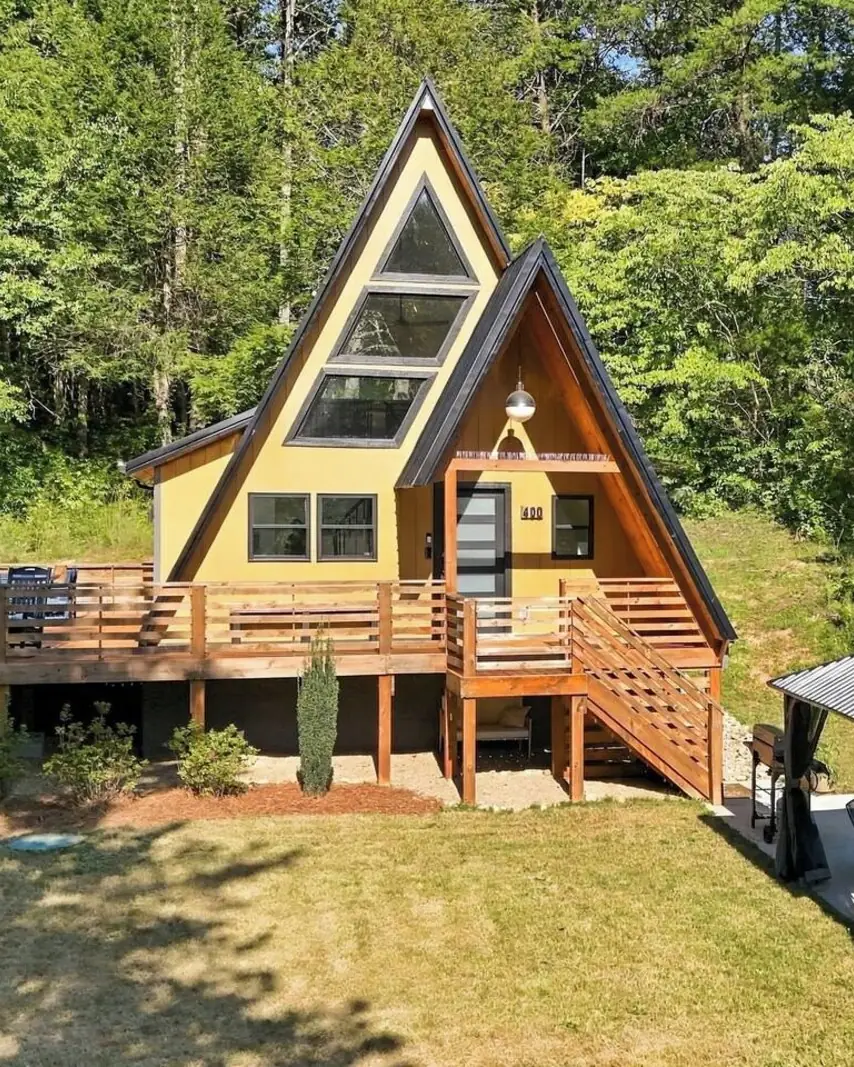 Acute cAbin, a golden A-frame with a long cedar deck, surrounded by tall trees